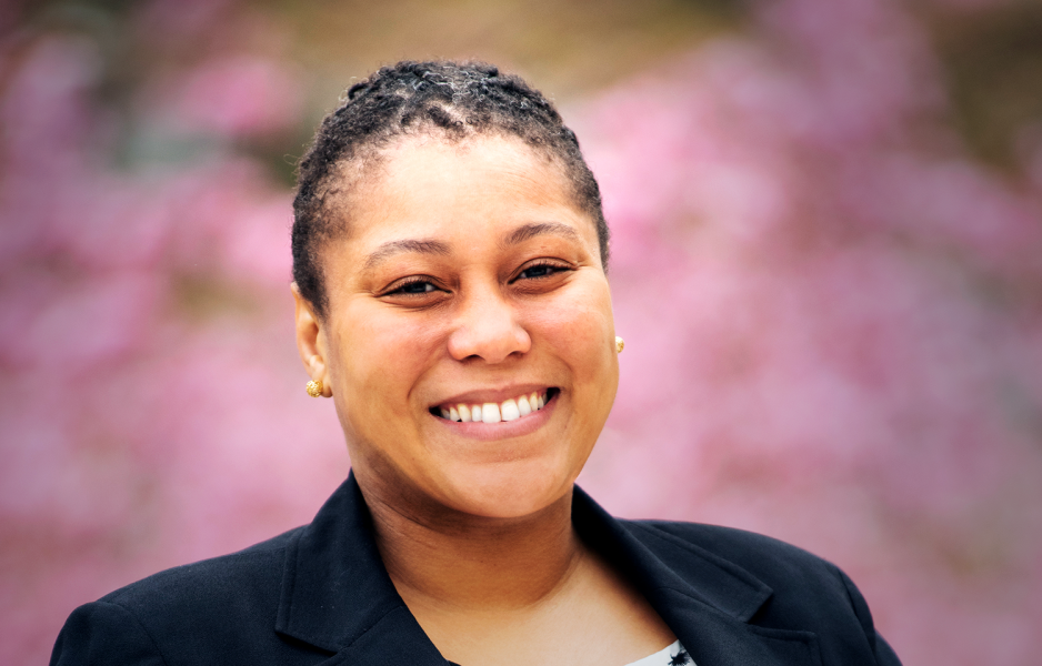 A young African American woman white short black hair, pearl necklace, and a dark blue suit